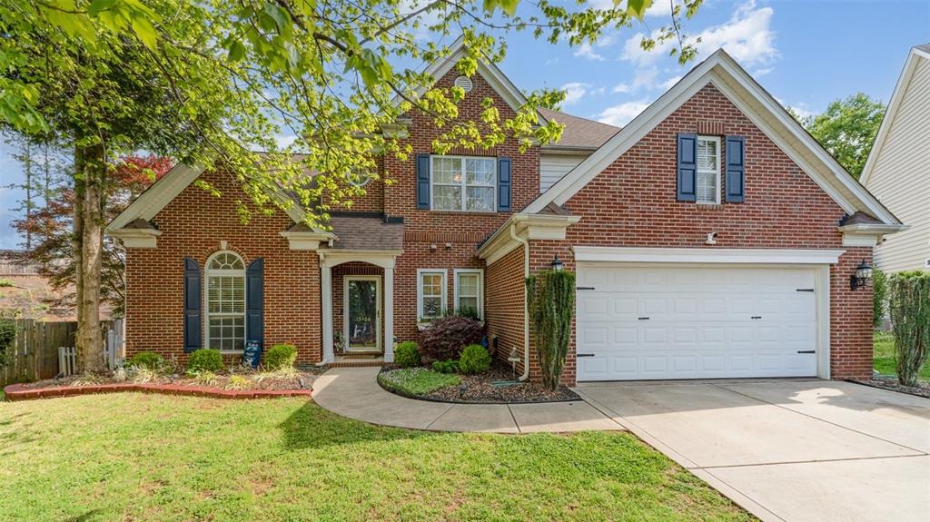 Red brick two-story home with a landscaped front yard and two-car garage